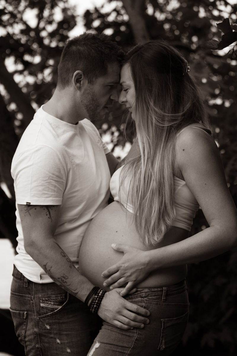 En attendant bébé — couple front contre front, mains sur le ventre rond