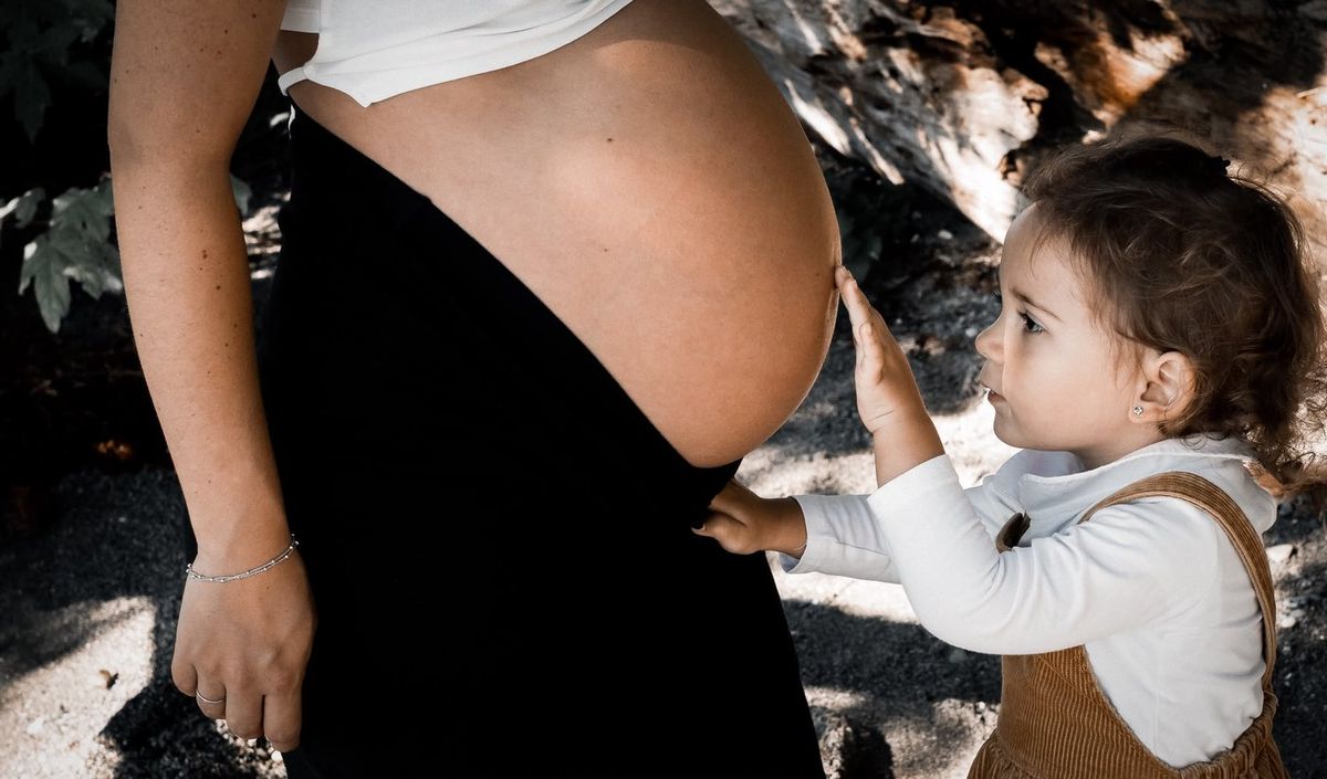 En attendant bébé — enfant touche le ventre de maman