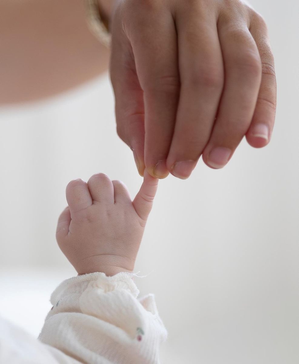 Famille — lifestyle en intérieur, main d'adulte et main de bébé