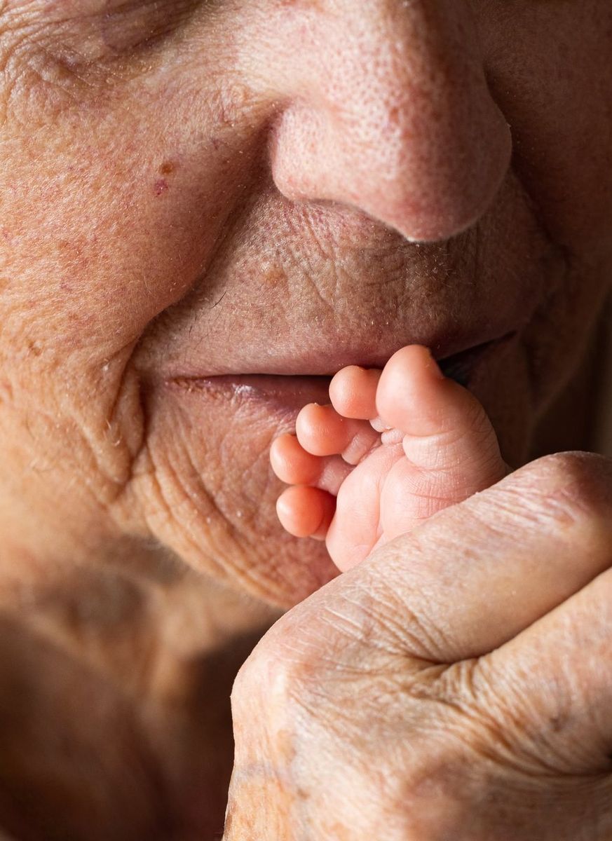 Intergénérationnel — pied de bébé contre le visage de l'aïeule