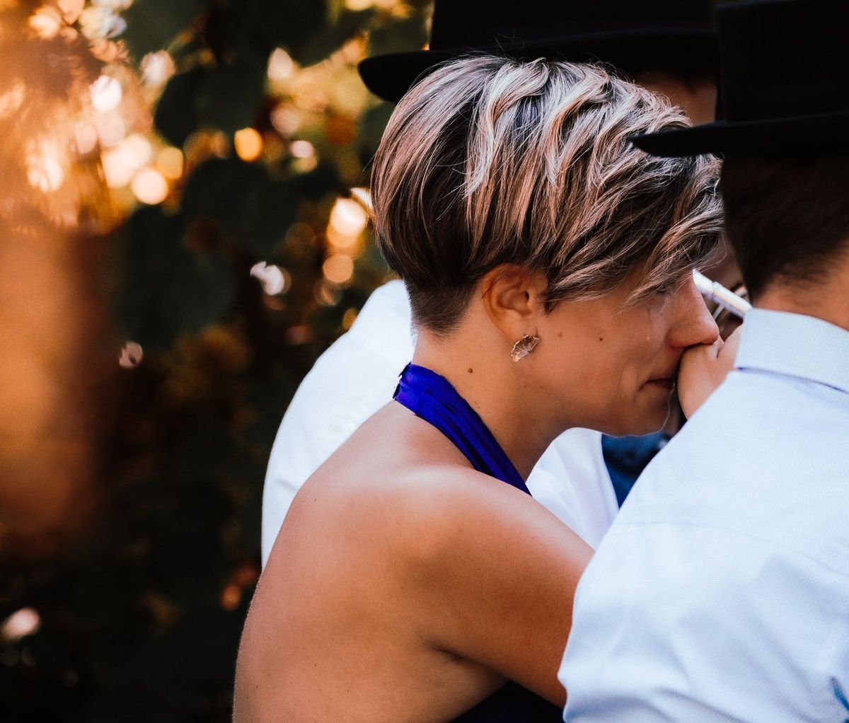 Mariage — séquence émotion, mariée émue enlacée au coucher du soleil