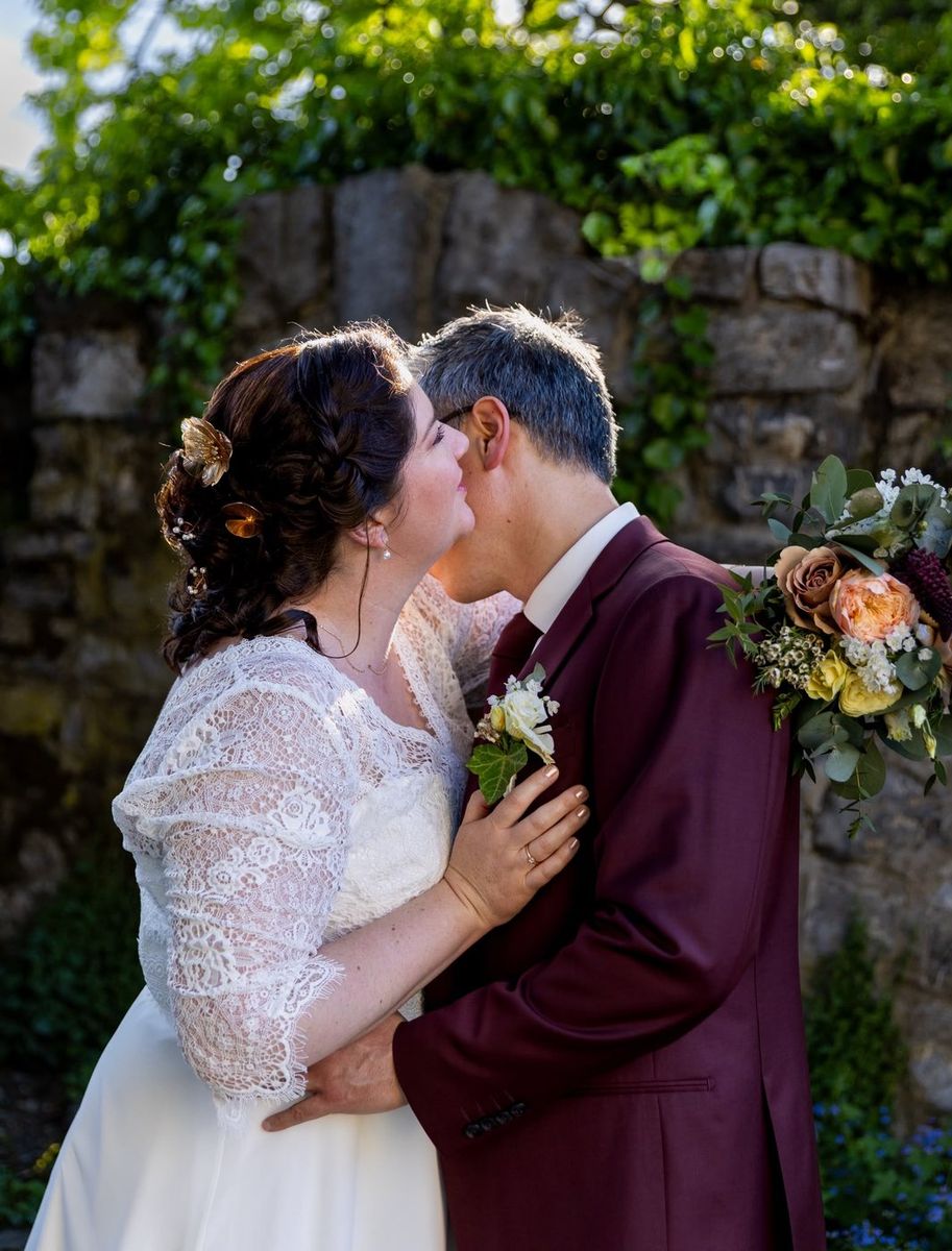 Mariage — baiser tendre des mariées devant le mur de verdure